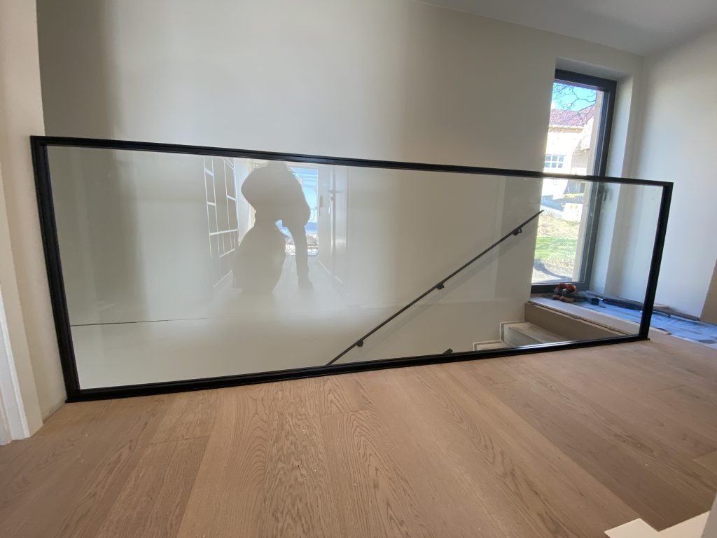 rekkverk i glass og svart metall langs trapp med minimalistisk design