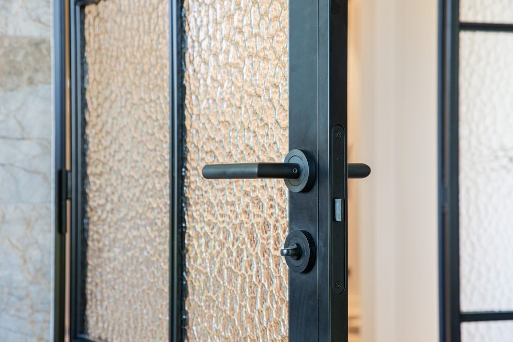 Glassdør i svart metall med mønstret glass og moderne håndtak
