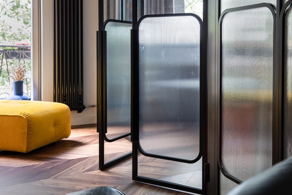 glassdør med rillet glass og sorte metallrammer i moderne interiør