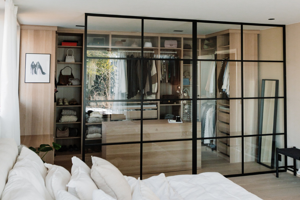 Glassvegg med svart metallramme og klart glass foran walk-in garderobe