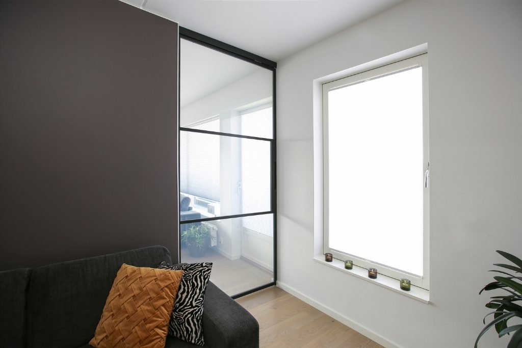 Innebygd skyvedør i metall og glass – praktisk og elegant løsning som går inn i veggen for plassbesparende rominndeling.