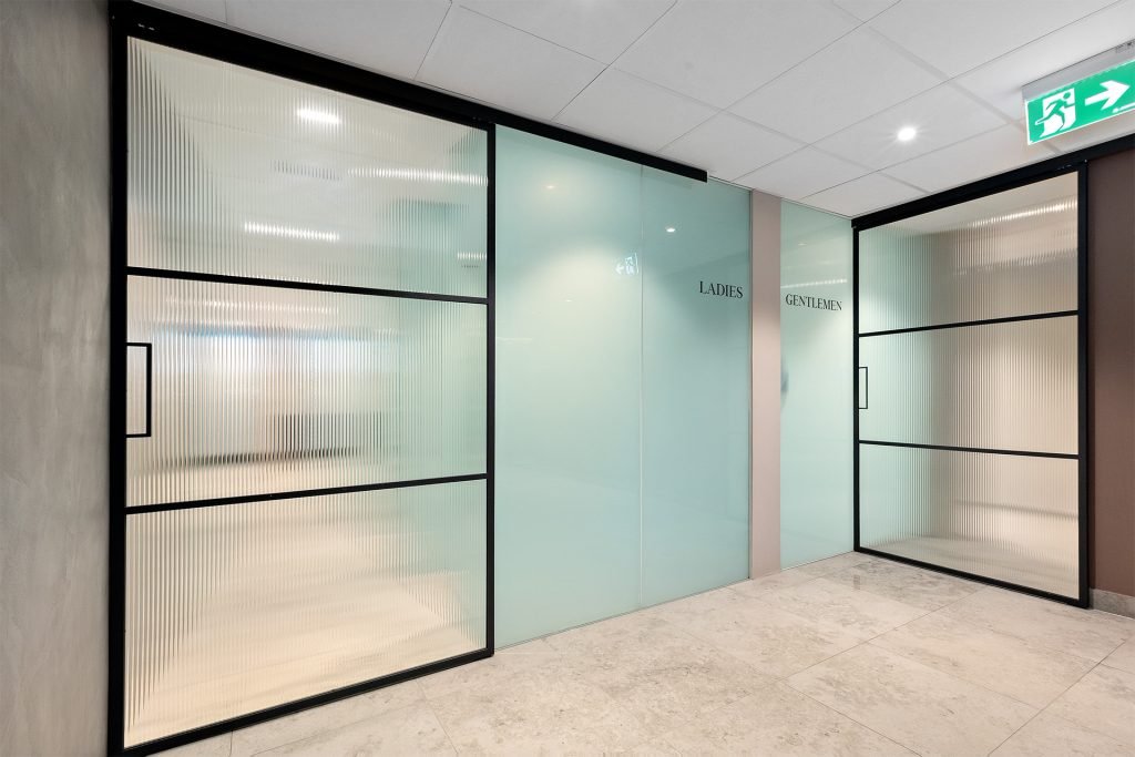 innendors skyvedorer i metall og rillet glass i moderne kontormiljo